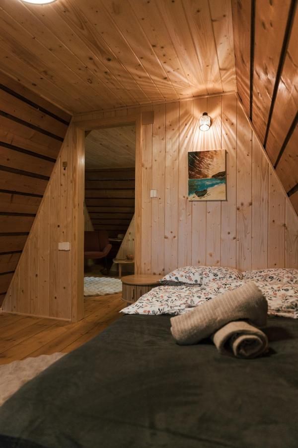 Sypialnia w domku z drewnianym sufitem i obrazem nad łóżkiem